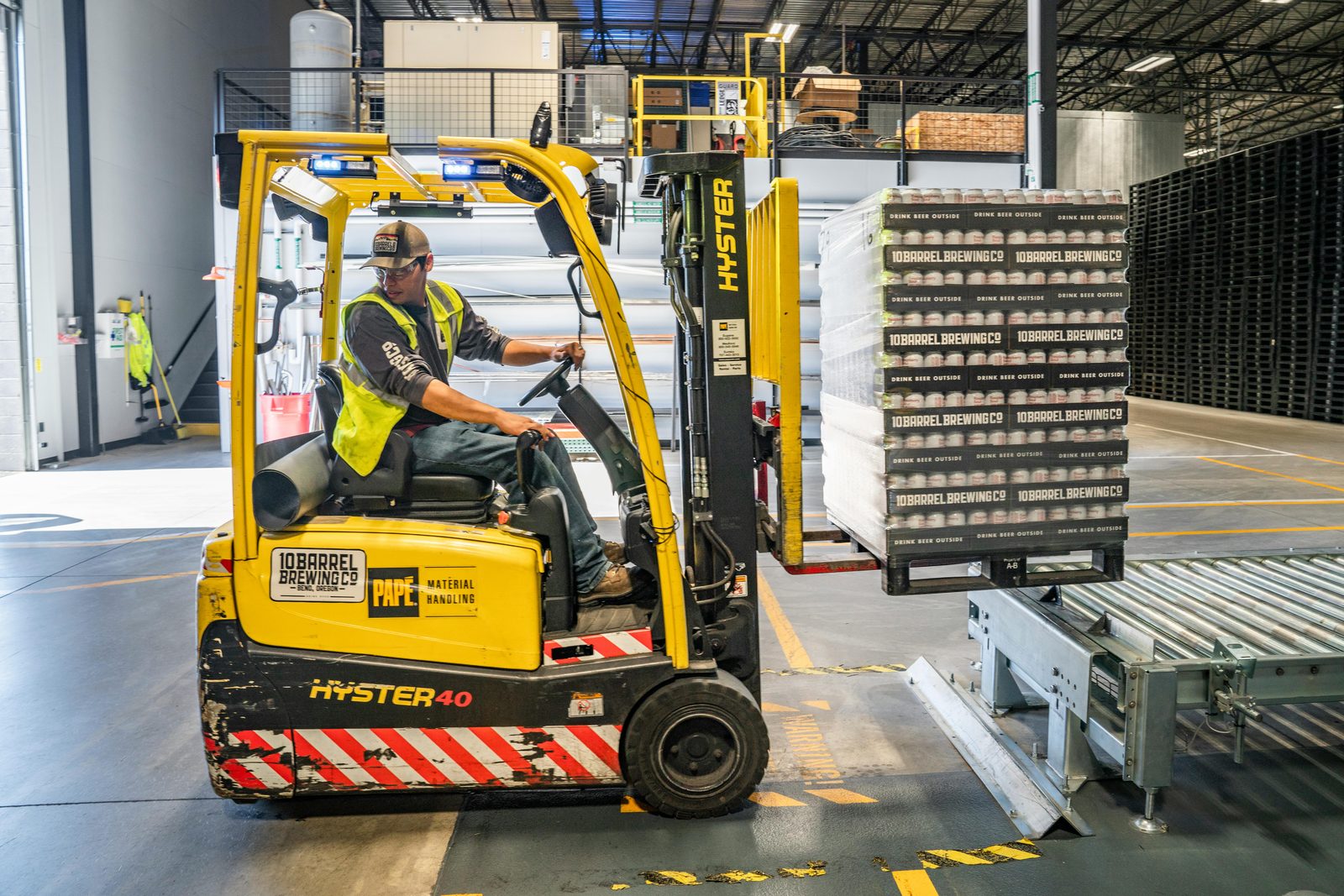 Forklift operator moving pallets inside a distribution warehouse